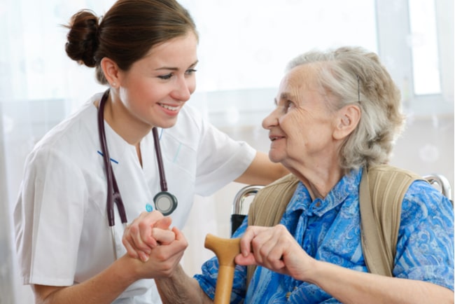 sjuksköterska håller äldre kvinna i handen