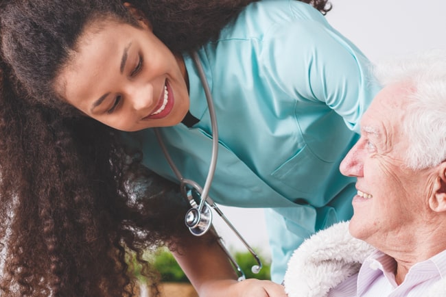 undersköterska ler mot äldre patient