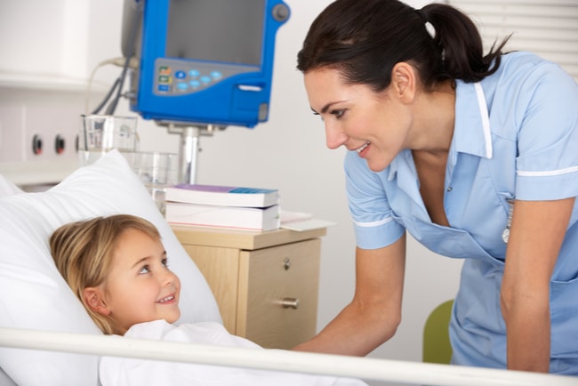 En barnsjuksköterska vårdar ett barn i sjuksäng