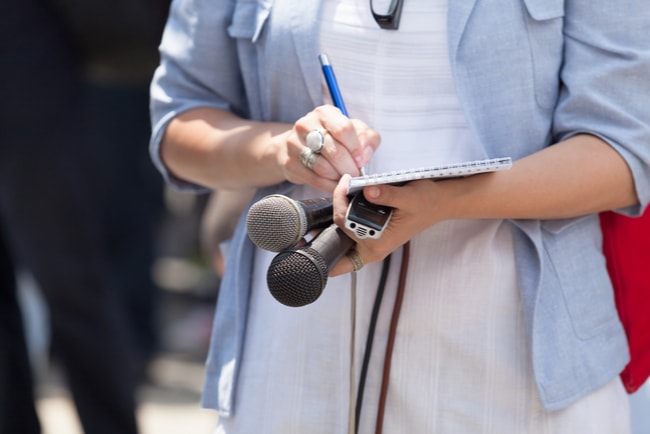 Kvinnlig journalist antecknar under en presskonferens